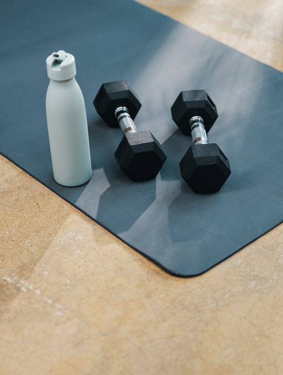 Water bottle and gym weights on yoga mat
